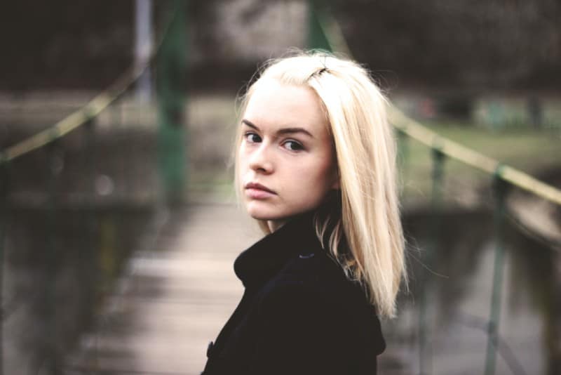 blonde woman in black jacket standing on bridge