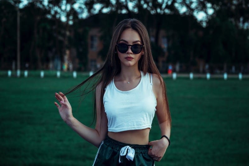 mujer con crop top blanco tocándose el pelo