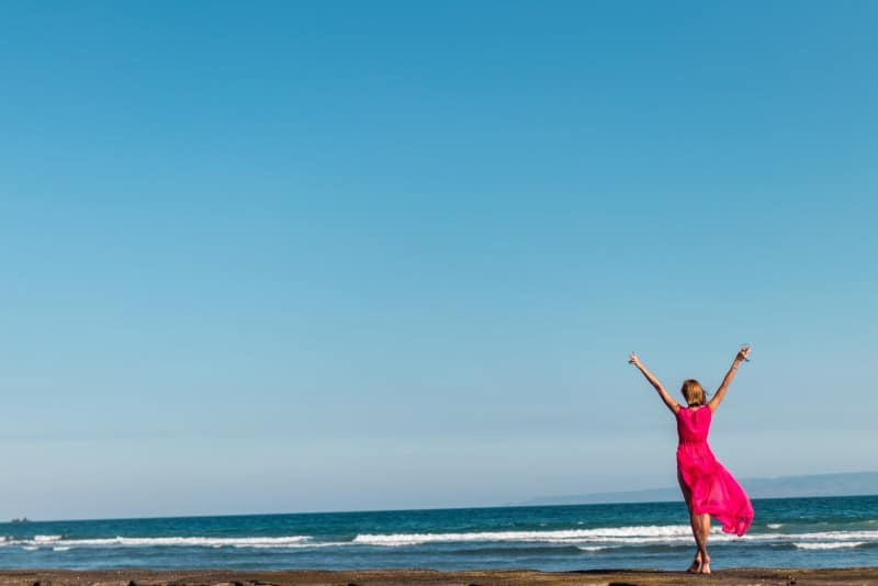 woman in pink dress standing on shore
