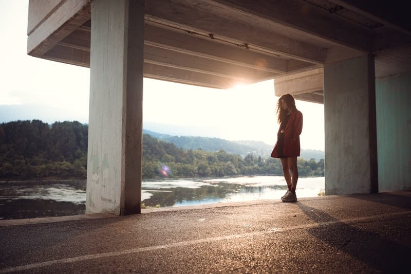 woman standing under concrete building
