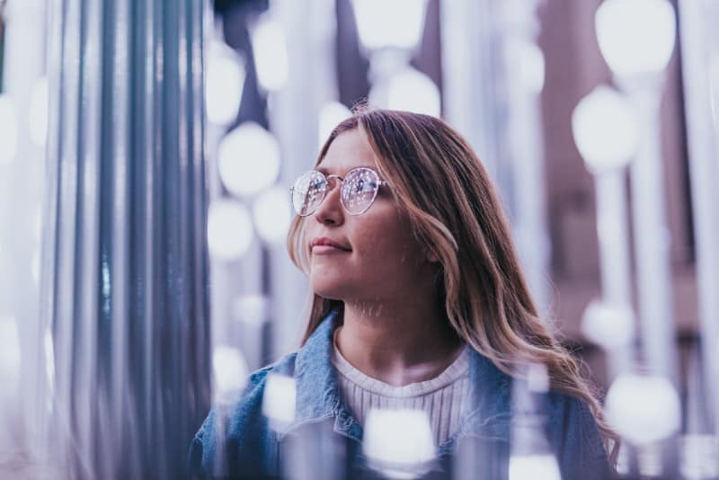 woman with glasses wearing denim jacket surrounded with bars