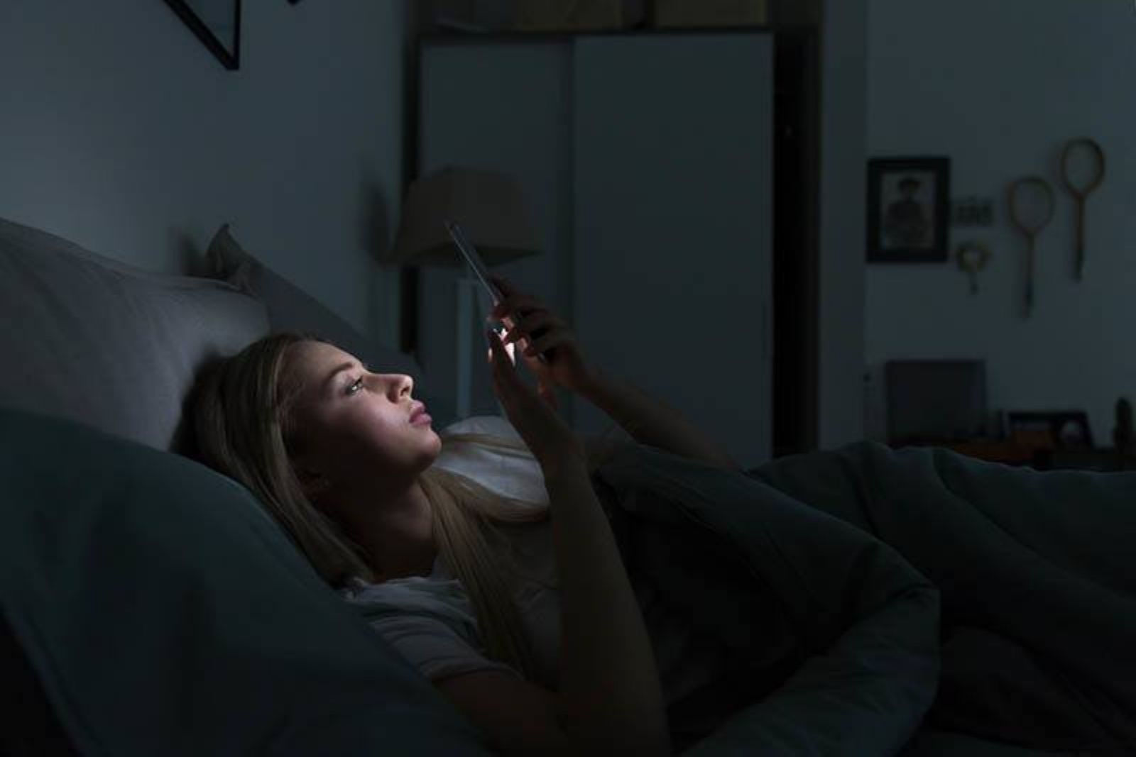 mujer tecleando su teléfono por la noche