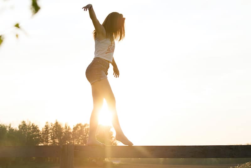 woman walking on the fence during the sunset