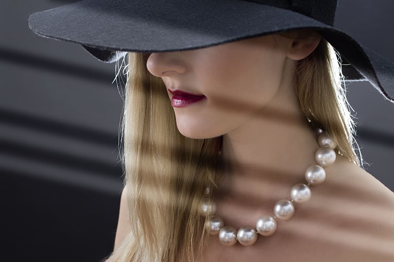 donna con cappello nero e collana di perle