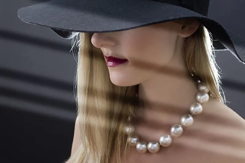 woman wearing black hat and pearl necklace