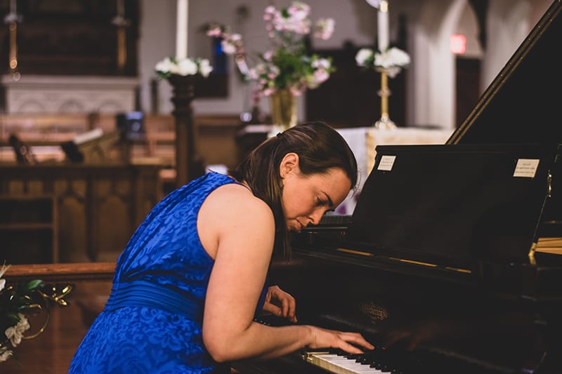 woman wearing blue floral dress playing piano