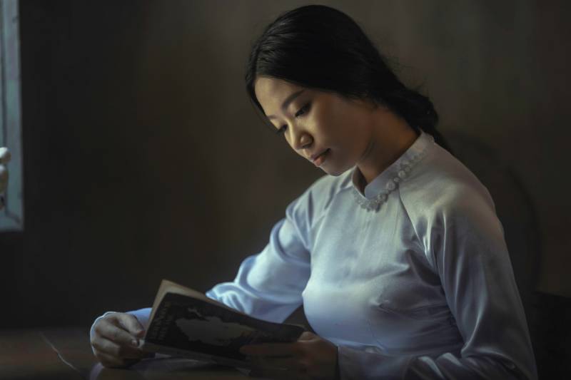 mujer con camiseta gris de manga larga leyendo un libro