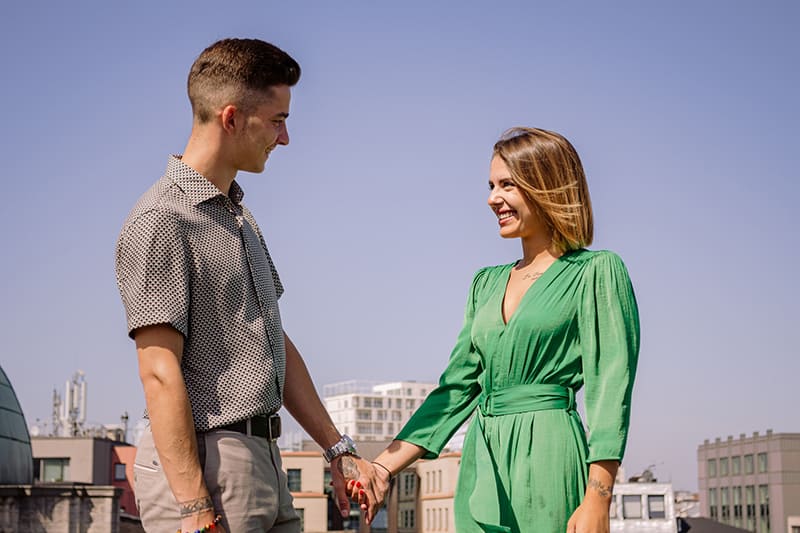 woman wearing green dress holding hands with man 