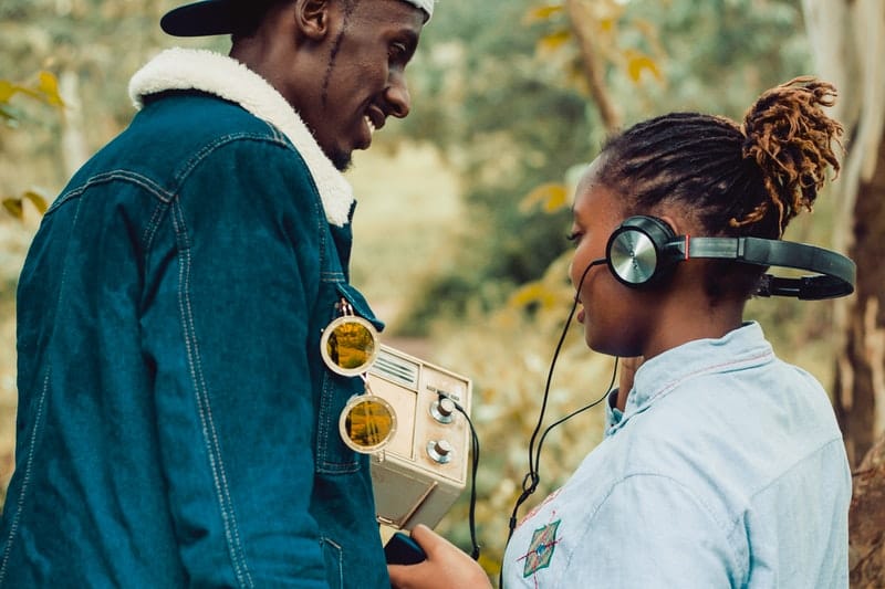 woman wearing headphones while a man standing beside her