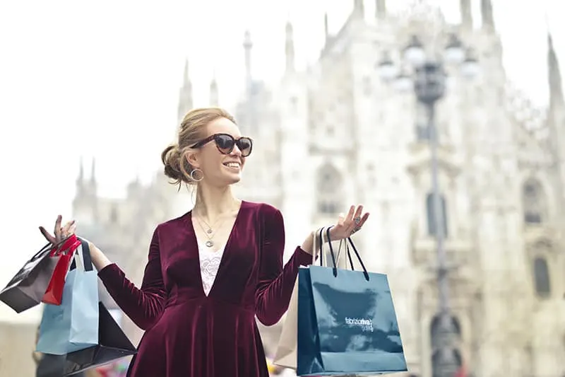 woman wearing maroon velvet long sleeved dress with shopping bags in her hands