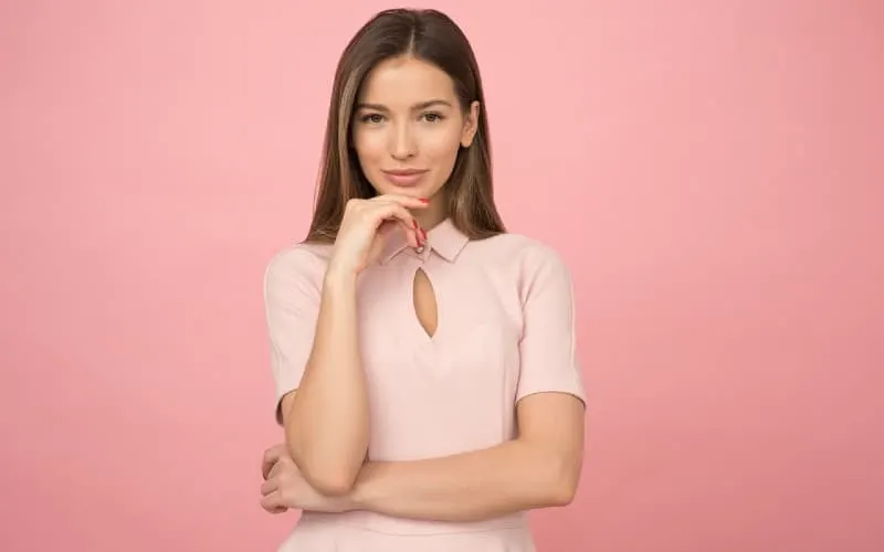 Woman wearing pink top standing against pink wall