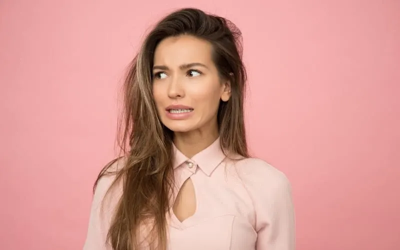 woman wearing pink top standing against pink wall