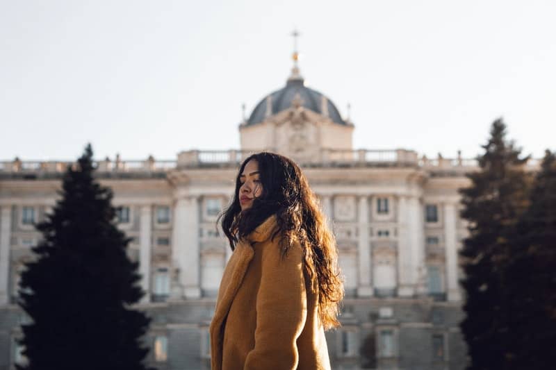 woman wearing winter coat passing by a big building