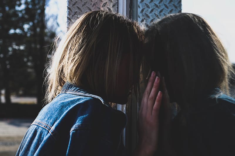 mujer con el pelo rubio de pie delante de la ventana