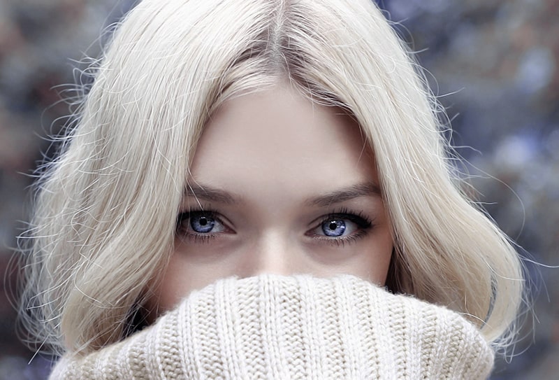 woman with blue eyes covering mouth with scarf