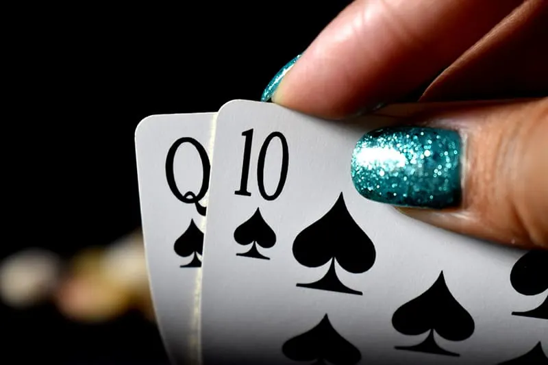 woman with blue nails holding playing cards