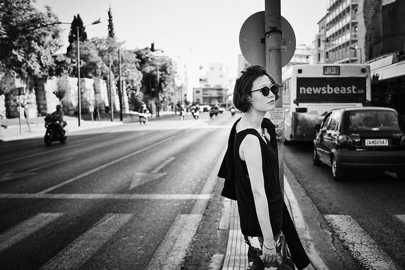 donna con taglio di capelli a caschetto che indossa occhiali da sole in piedi accanto alla segnaletica stradale