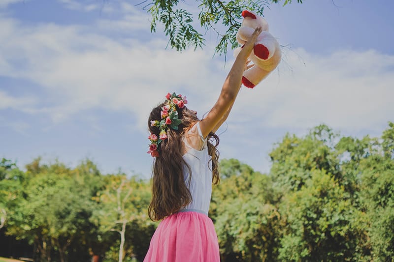 mujer con flores en el pelo sosteniendo un osito de peluche