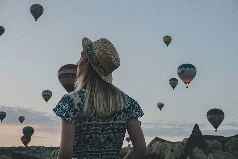 woman with hat looking at flying balloons
