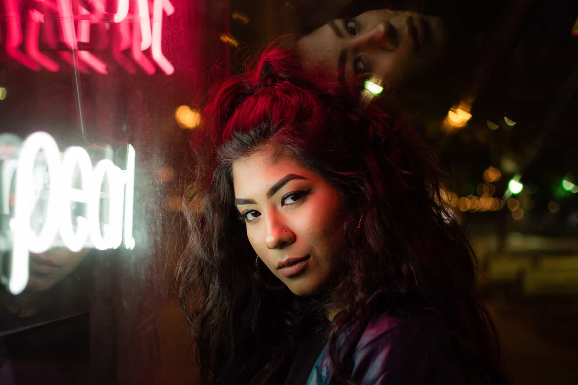 woman with long wavy hair standing near neon signages