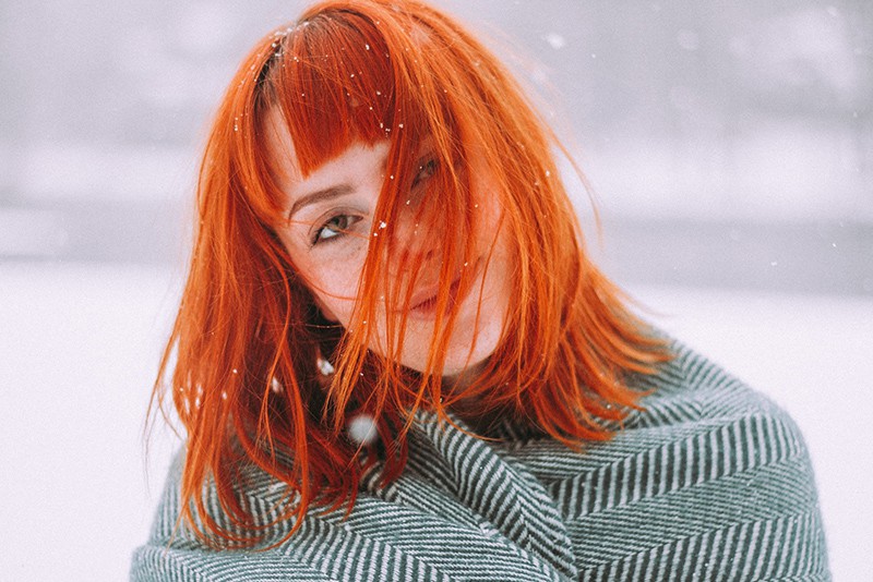 woman with red hair standing while is snowing