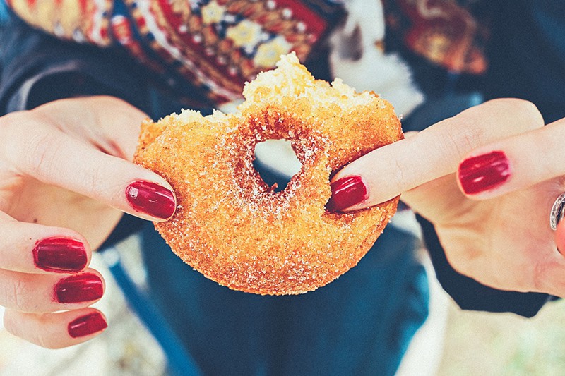 mujer con uñas rojas sosteniendo un donut