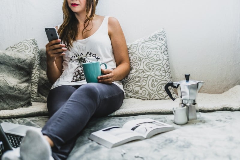 mujer con pintalabios rojo usando smartphone en la cama