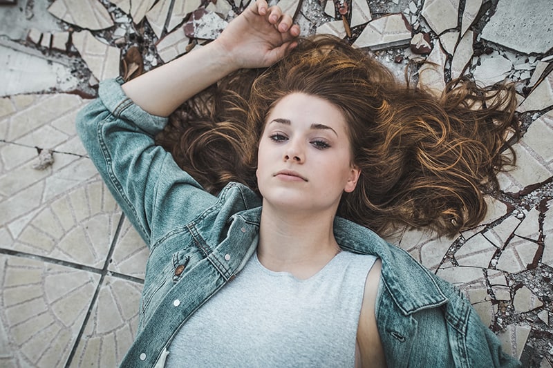 woman with splayed out hair lying on crack tiles