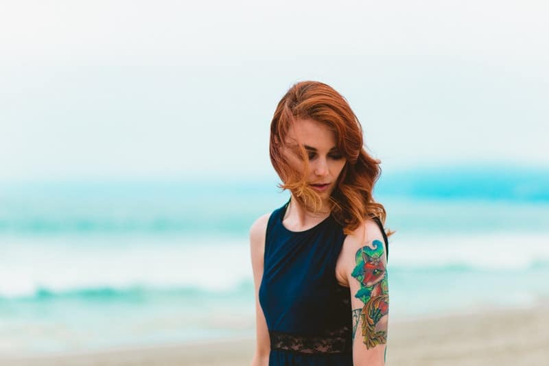 donna con tatuaggio vicino al mare blu