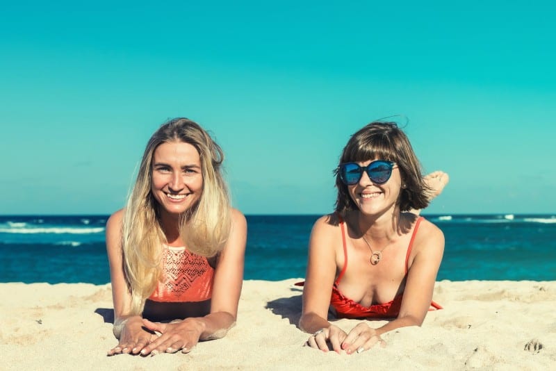 two women in bikinis laying on beach
