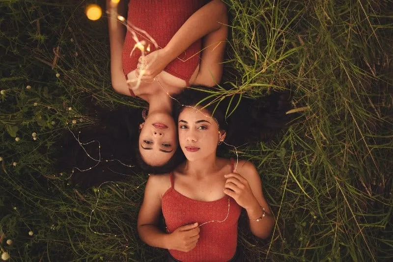 two female twins in red tops lying on grass