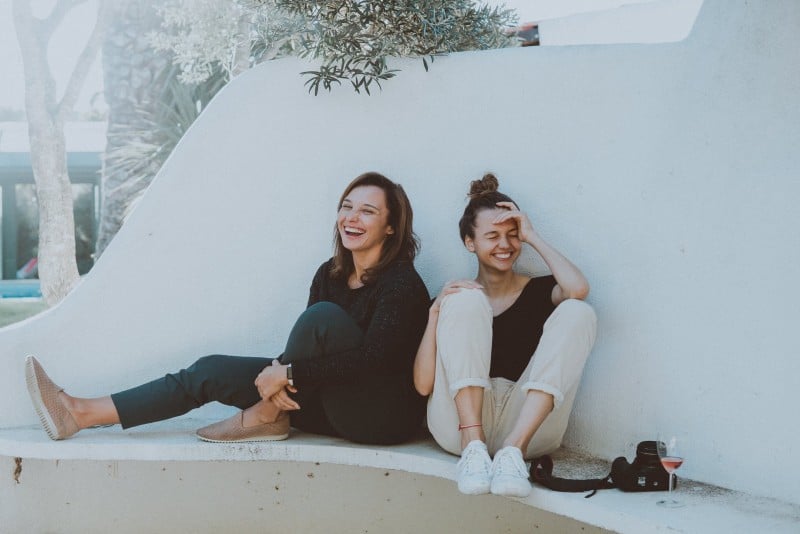 two women sitting on white bench and smiling