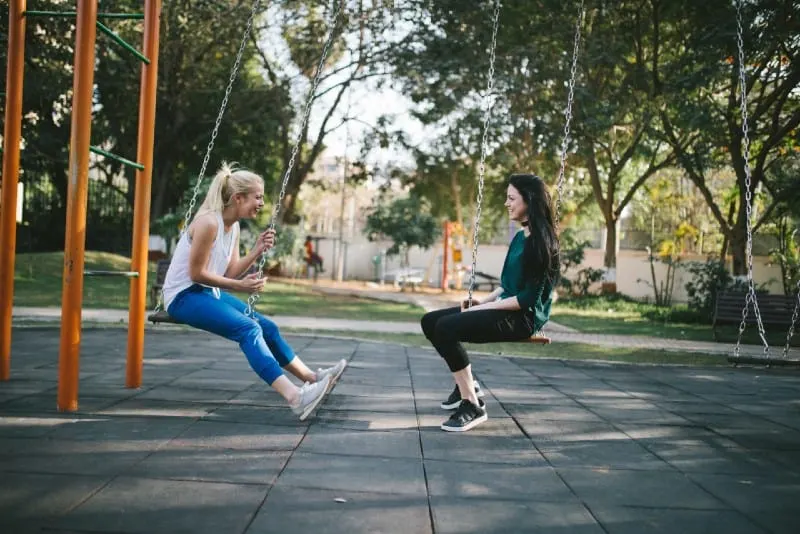 two women sitting on swing and talking