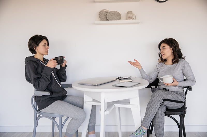 women talking to each other while holding cups