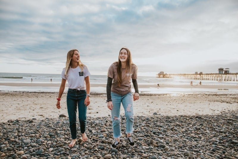 two women walking on pebbles and laughing