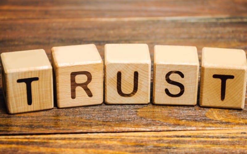 Wooden blocks forming the word trust on a brown wood background