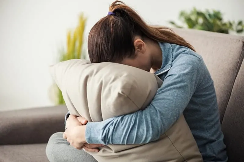worried woman hugging pillow at home
