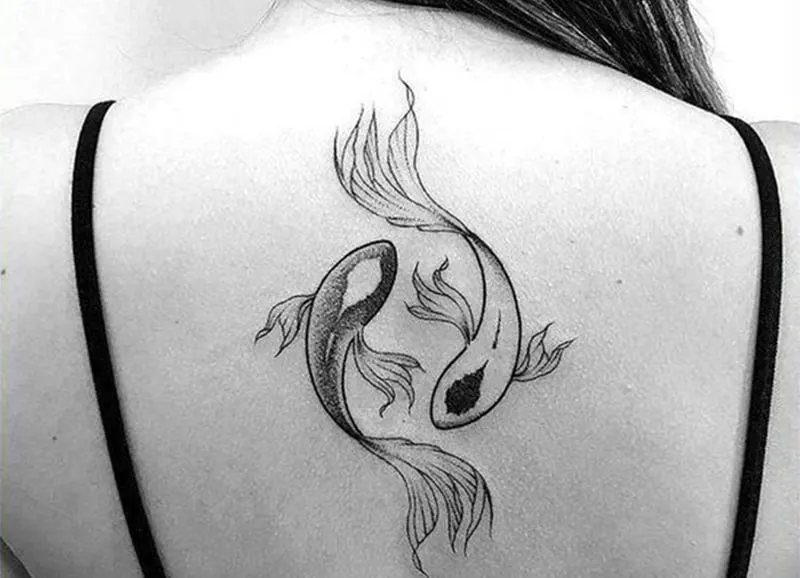 yin yang tattoo of pisces on woman`a back
