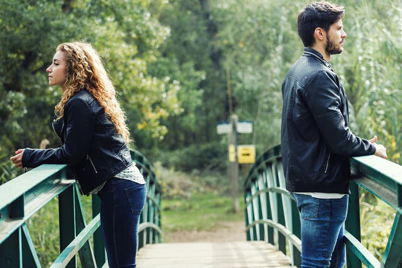 joven pareja en conflicto de pie en el puente