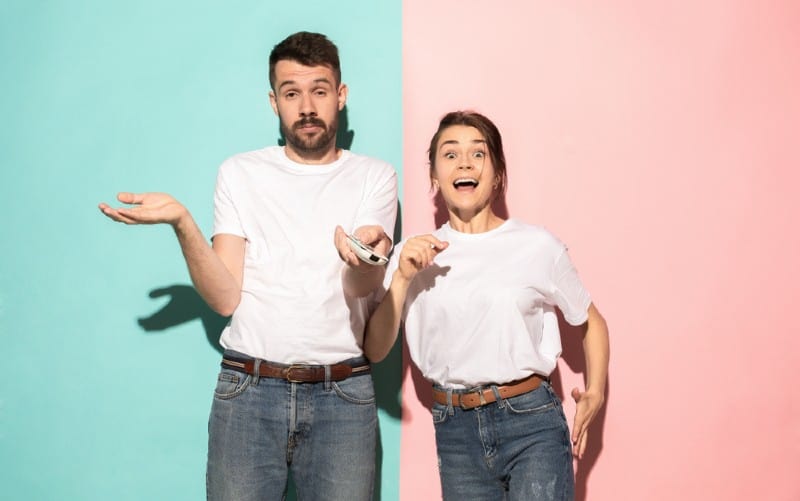 Young funny couple standing against blue and pink wall