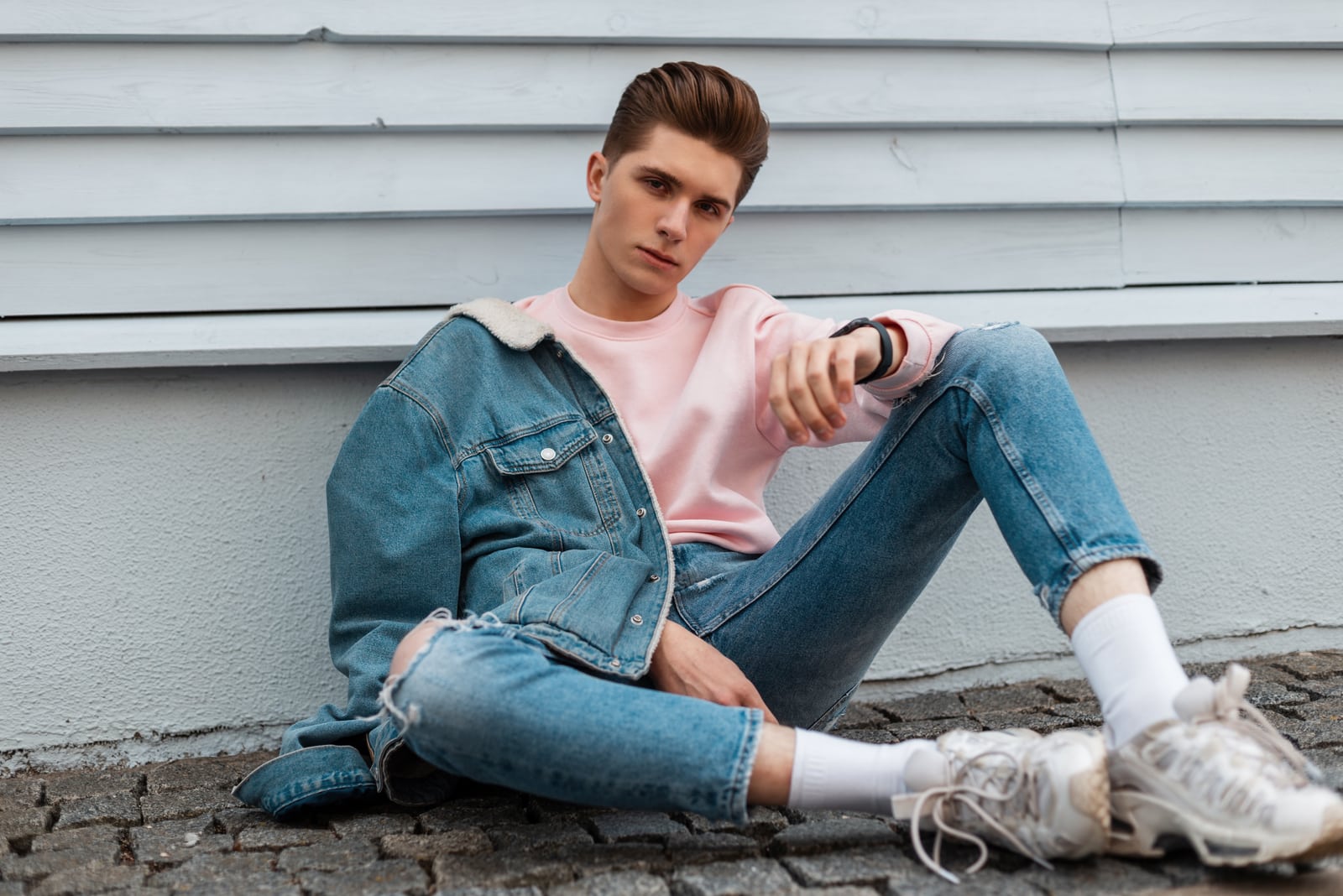 young man in stylish denim jacket in ripped fashionable blue jeans