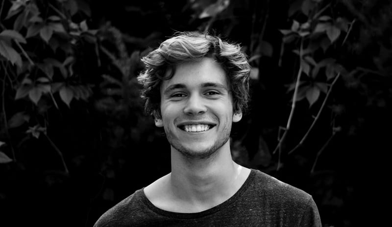 young man smiling surrounded with trees