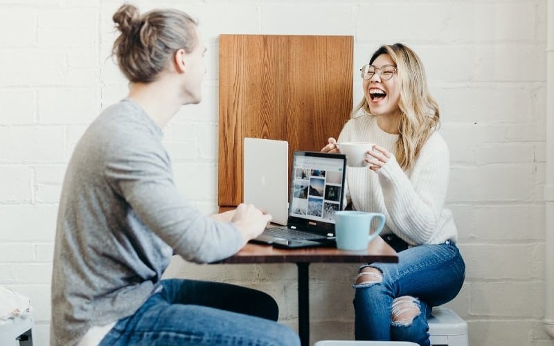 Young man with laughing young woman sitting at a table