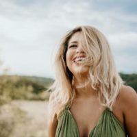 mujer rubia con top verde sonriendo al aire libre