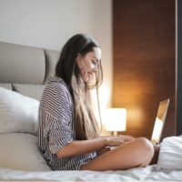 Mulher feliz com um computador portátil na cama