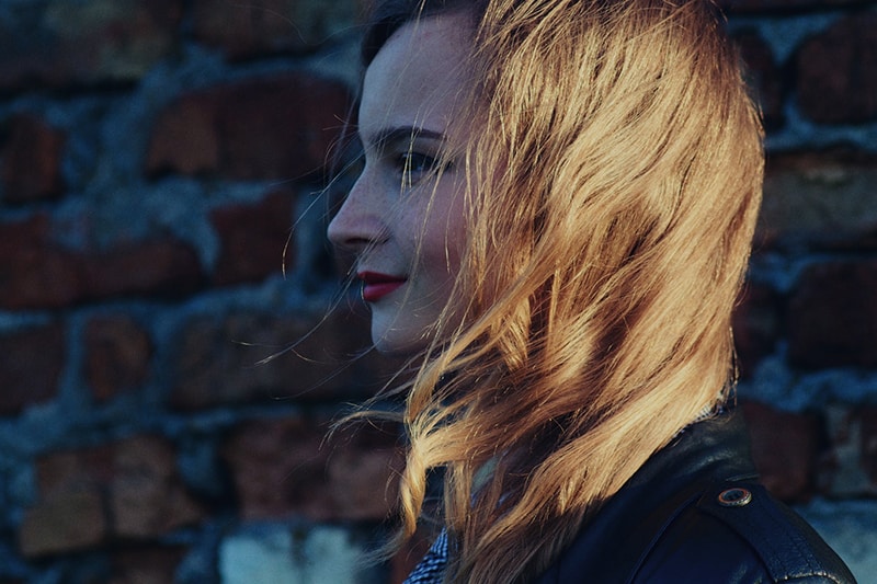 smiling woman standing near brick wall