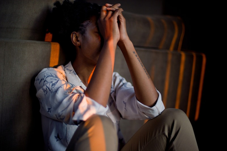 woman sitting on the floor while leaning on the sofa