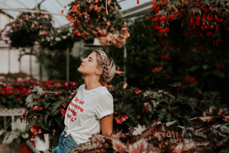 woman with eyes closed standing near flowers