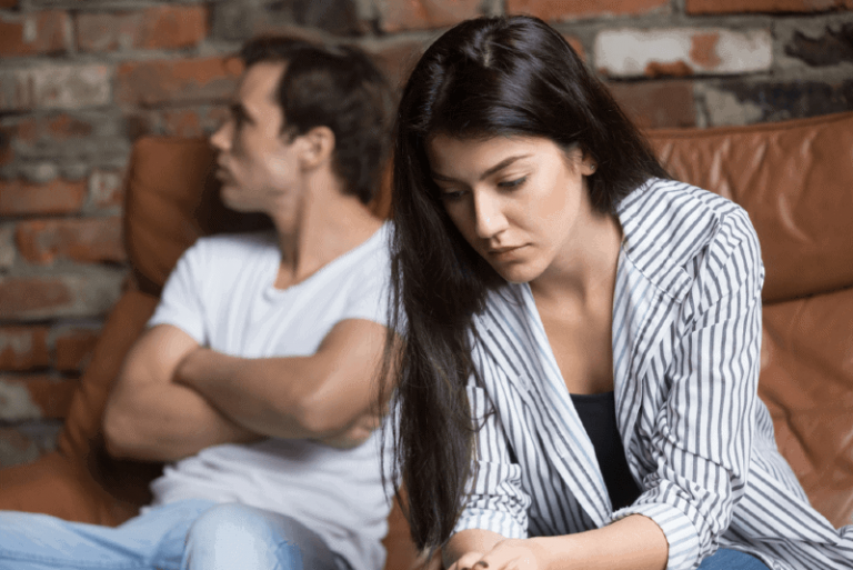 sad woman sitting on couch near man