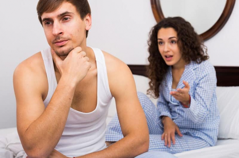 mulher de pijama a chatear um homem de camisola interior branca sentado na cama